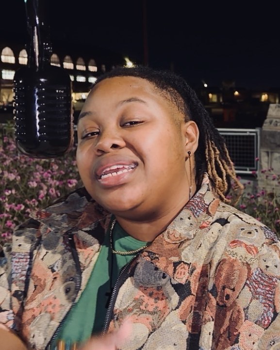 CreNaetive smiling at the microphone outdoors at night